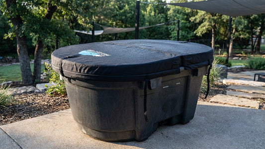 A stock tank cold plunge with an insulated hard foam cover in a well maintained backyard.