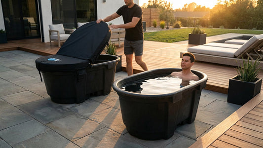 Two men use cold plunge tanks in a backyard setting. One man is already nestled in his tank, the other is removing the hard insulated cover for this stock tank cold plunge.
