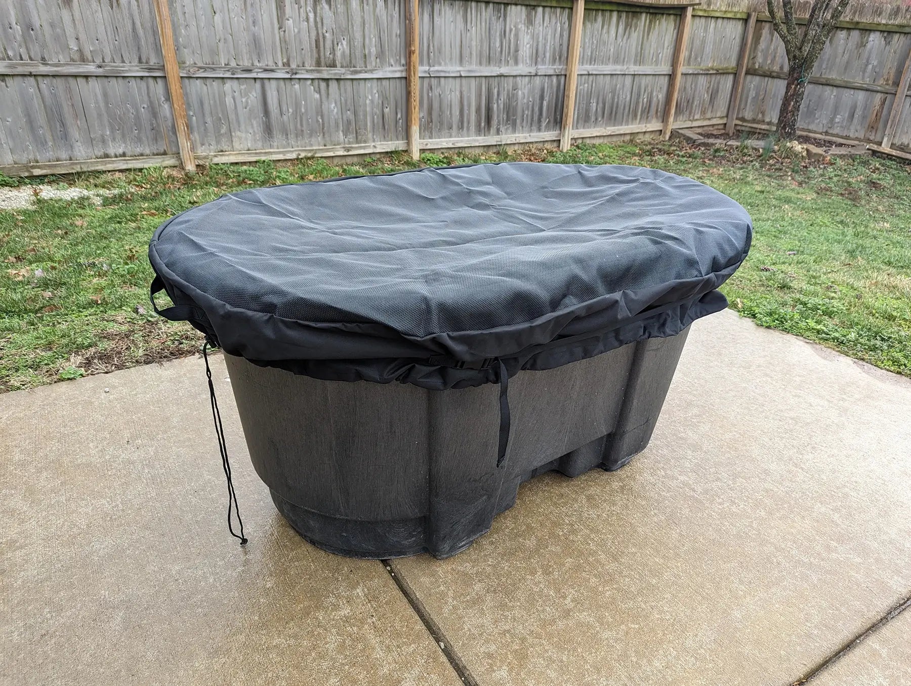 In use image of a 100 gallon stock tank with a tight fitting mesh insert cover. The mesh insert keeps debris and predators out, but lets light and air in, making it a perfect solution for raising chicks or fish.