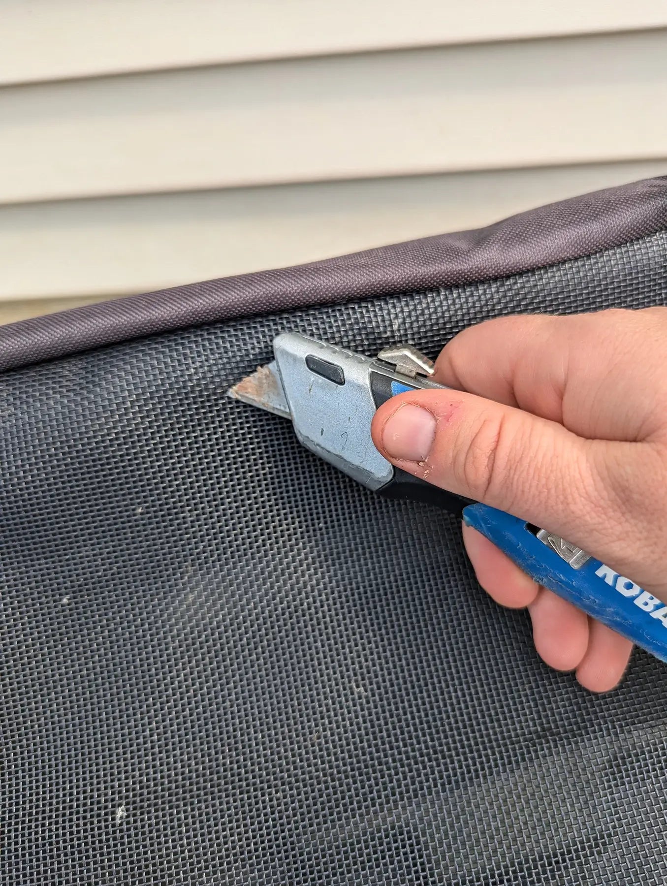 A utility knife struggles to cut through the rip- and tear-proof mesh cover. The mesh stock tank cover is a durable solution for ranchers and farmers.